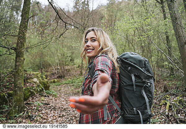 Smiling blond backpacker hiking in forest