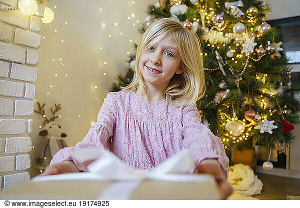 Smiling blond girl with Christmas present at home