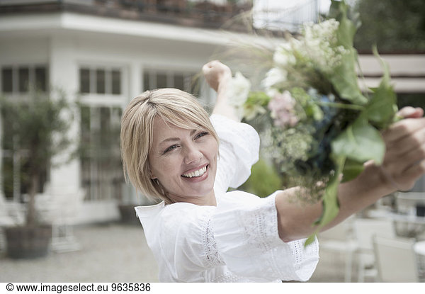 Smiling blond woman holding wedding bouquet