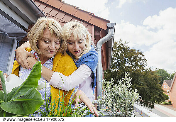 Smiling blond woman hugging mother in balcony