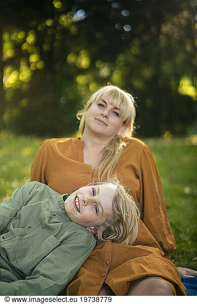 Smiling blond woman with boy relaxing in park