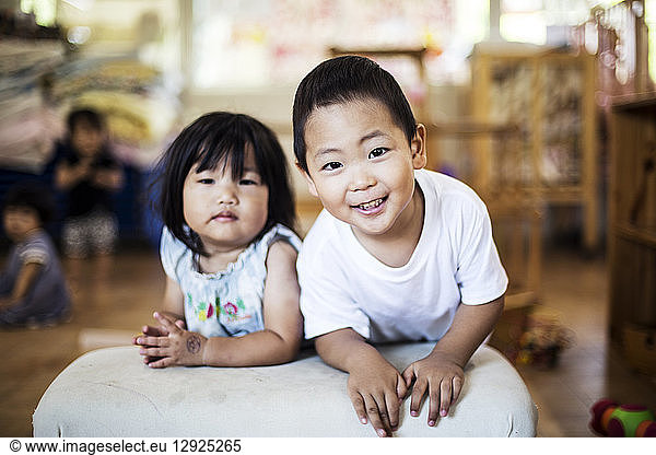Smiling boy and girl in a Japanese preschool  looking at camera.