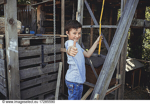 Smiling boy doing thumbs up in back yard
