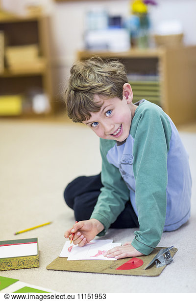 Smiling boy drawing in classroom