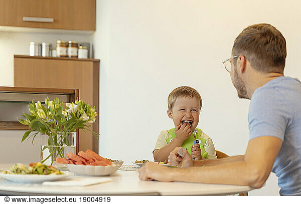 Smiling boy having breakfast with father at home