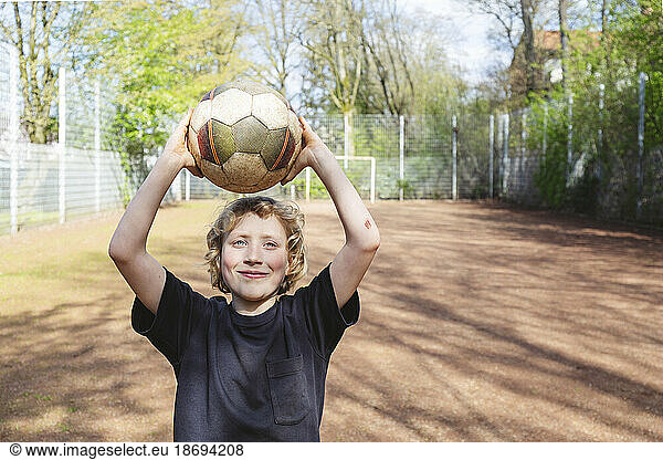 Smiling boy holding soccer ball on playground