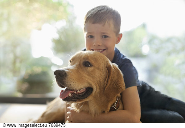 Smiling boy hugging dog indoors