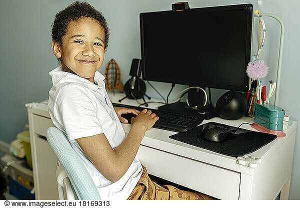 Smiling boy in front of desktop PC at home