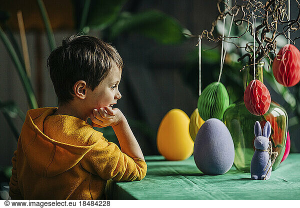 Smiling boy looking at Easter decoration on table at home