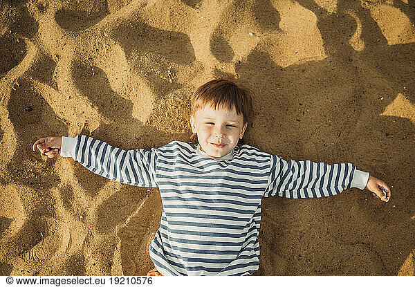 Smiling boy lying on beach sand