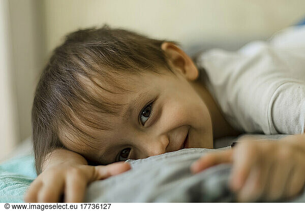 Smiling boy lying on bed at home
