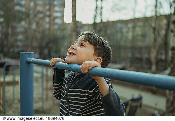 Smiling boy playing on monkey bar at park