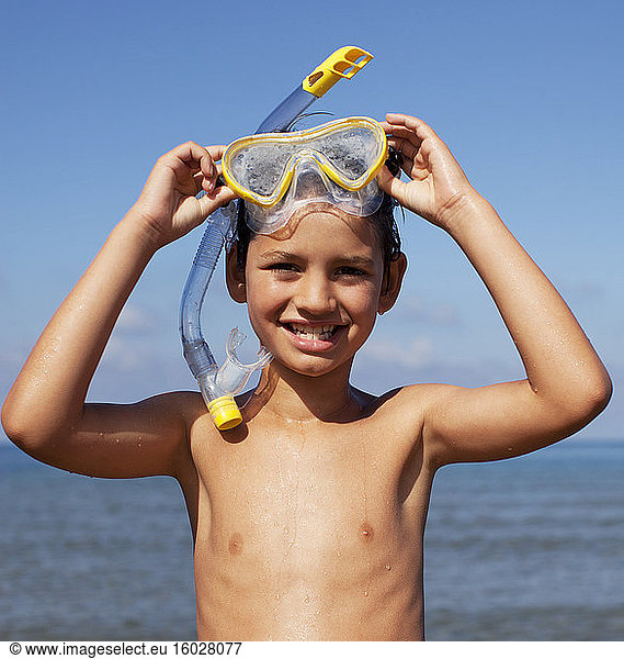 Smiling boy removing snorkel and goggles
