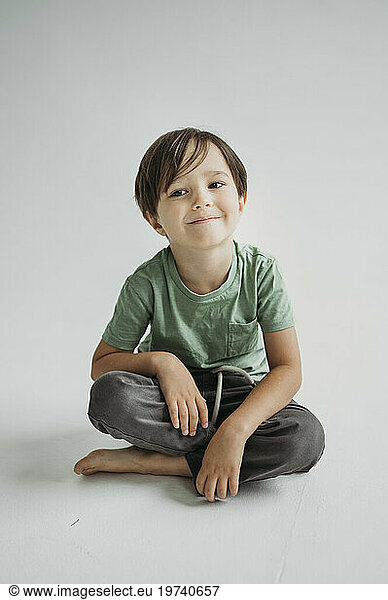 Smiling boy sitting against white background