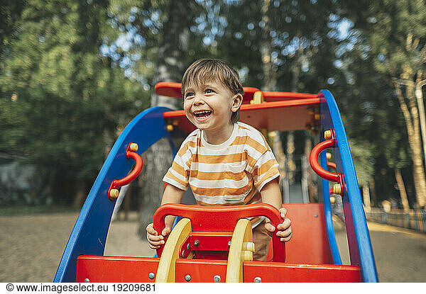 Smiling boy sitting on play equipment in park