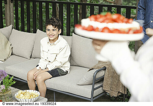 Smiling boy sitting on sofa at patio
