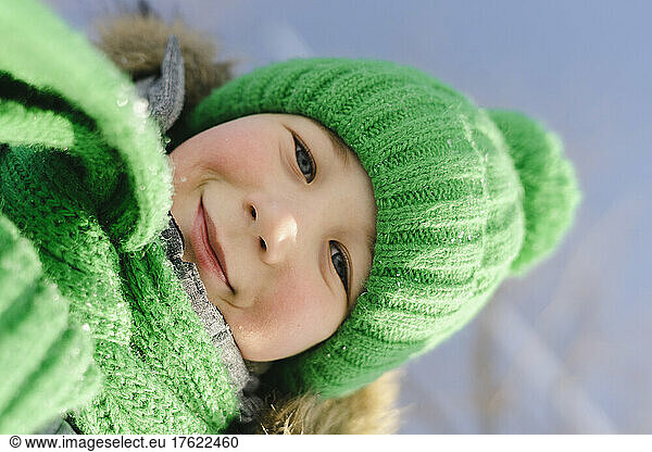 Smiling boy wearing green knit hat and scarf