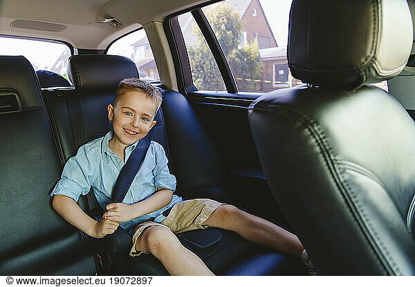 Smiling boy wearing seat belt in car