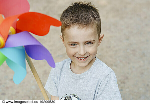 Smiling boy with colorful rainbow pinwheel toy