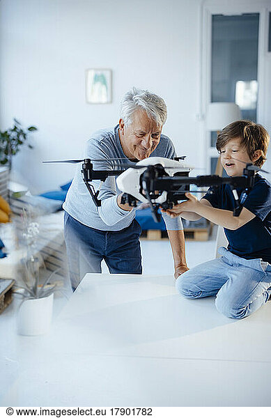 Smiling boy with grandfather flying drone at home