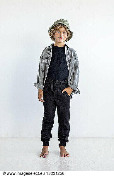 Smiling boy with hand in pocket standing against white background