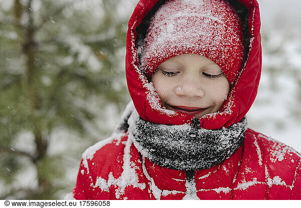 Smiling boy with snow on knit hat and warm clothing in winter
