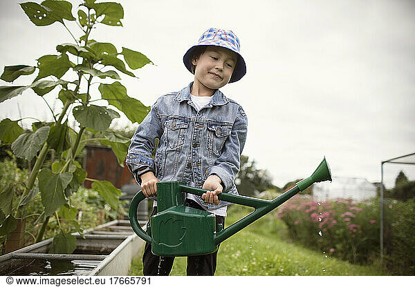 Smiling boy with watering can in garden