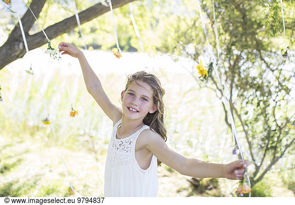 Smiling bridesmaid playing with decorations in domestic garden during wedding reception