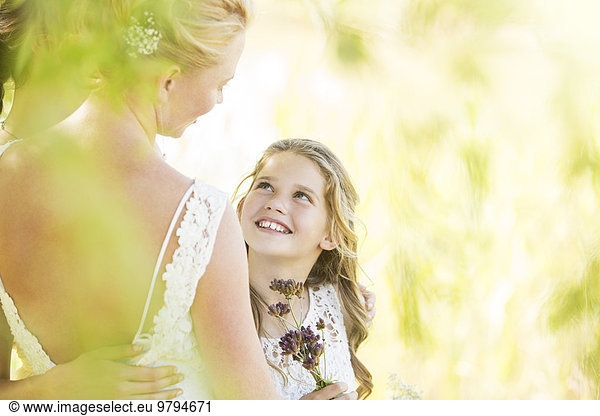 Smiling bridesmaid with flowers and bride during wedding reception in garden