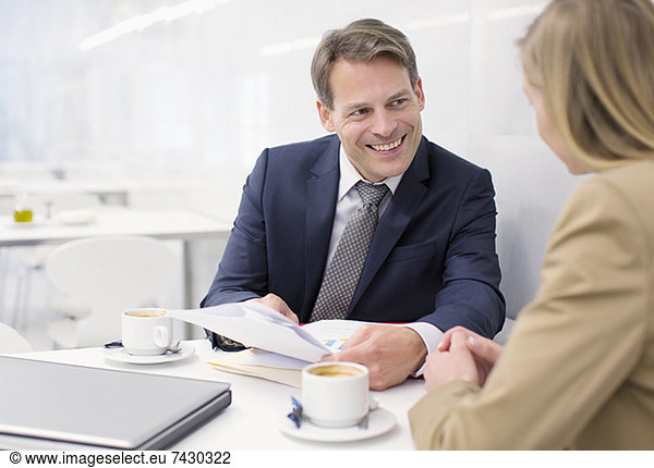 Smiling business people discussing paperwork in cafe