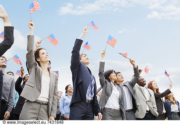 Smiling business people in crowd waving American flags