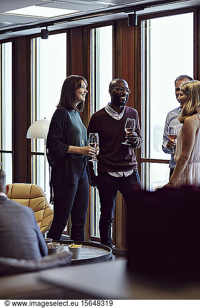 Smiling business professionals discussing over drinks during conference at office