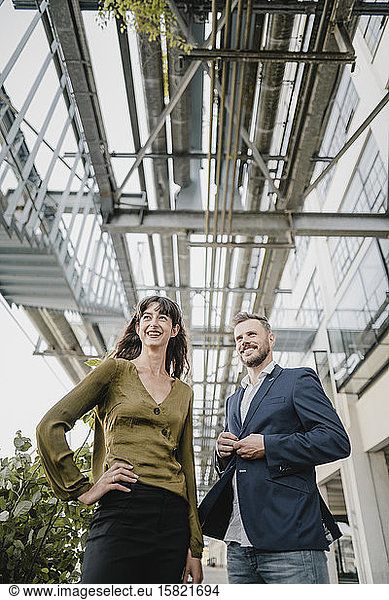 Smiling businessman and casual businesswoman standing outdoors