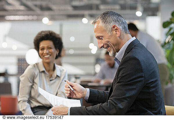 Smiling businessman discussing with colleague in office