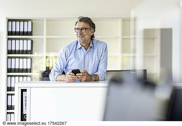 Smiling businessman holding tablet PC at office