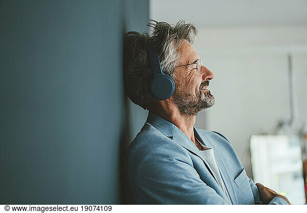Smiling businessman listening to music at office