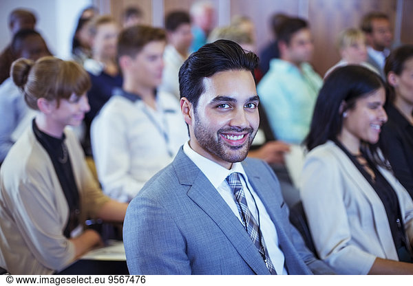 Smiling businessman sitting in conference room and looking at camera