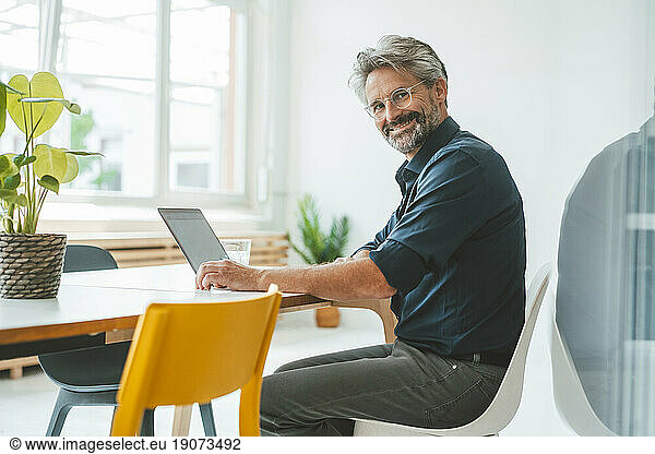 Smiling businessman sitting on chair in office