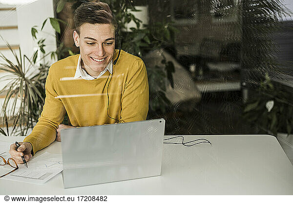 Smiling businessman talking through video conference at home office