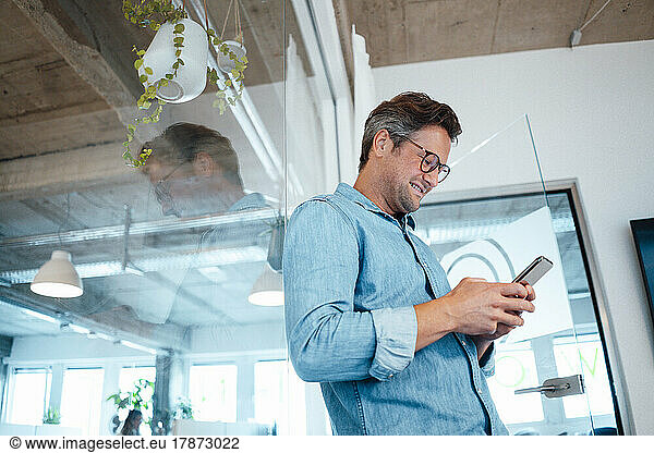 Smiling businessman using smart phone in office