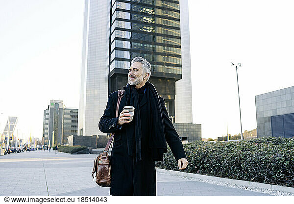 Smiling businessman walking with coffee cup