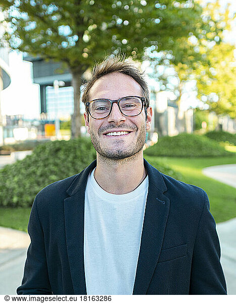 Smiling businessman wearing eyeglasses at office park