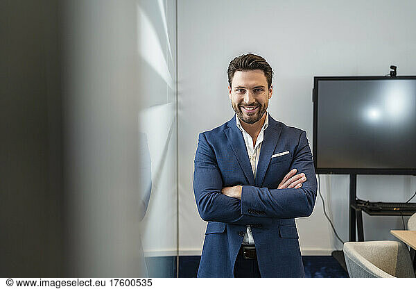 Smiling businessman with arms crossed standing in office
