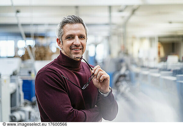 Smiling businessman with eyeglasses in factory