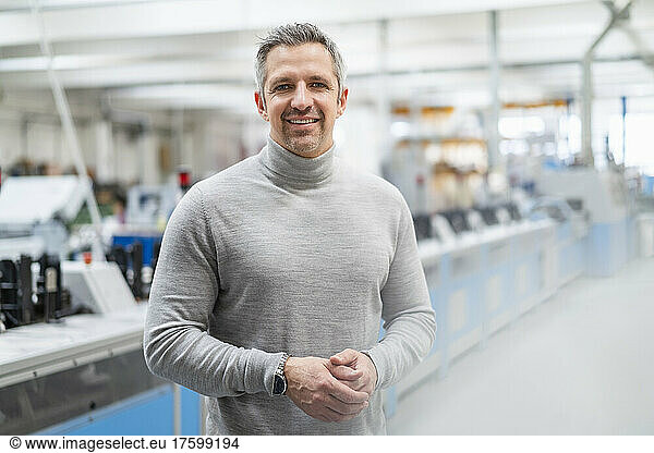 Smiling businessman with gray hair in factory