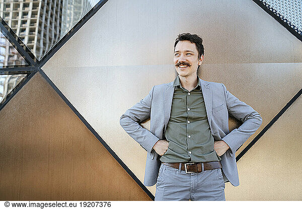Smiling businessman with mustache standing in front of modern office building