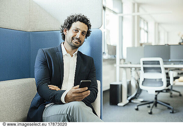 Smiling businessman with smart phone in office