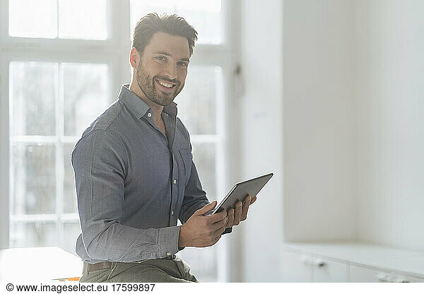Smiling businessman with tablet PC in office