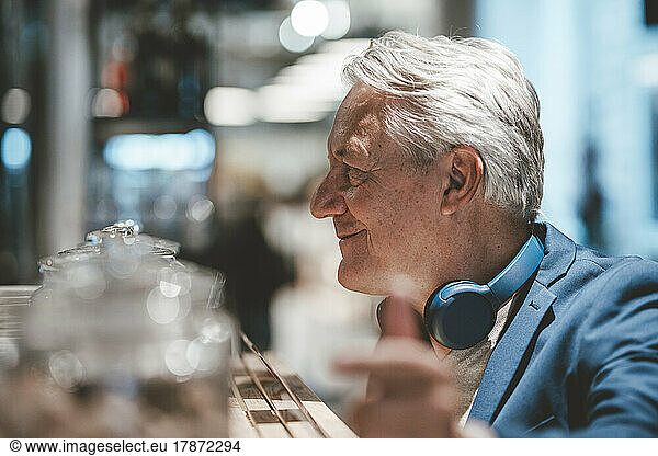 Smiling businessman with wireless headphones at cafe