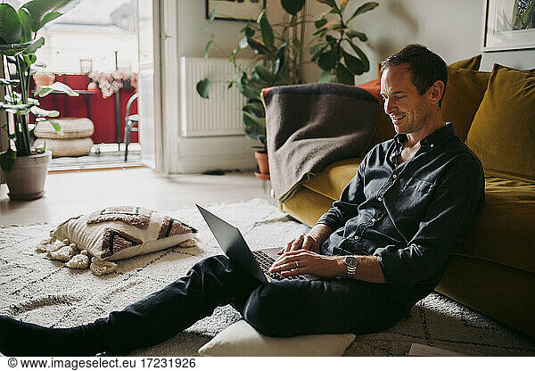 Smiling businessman working on laptop in living room